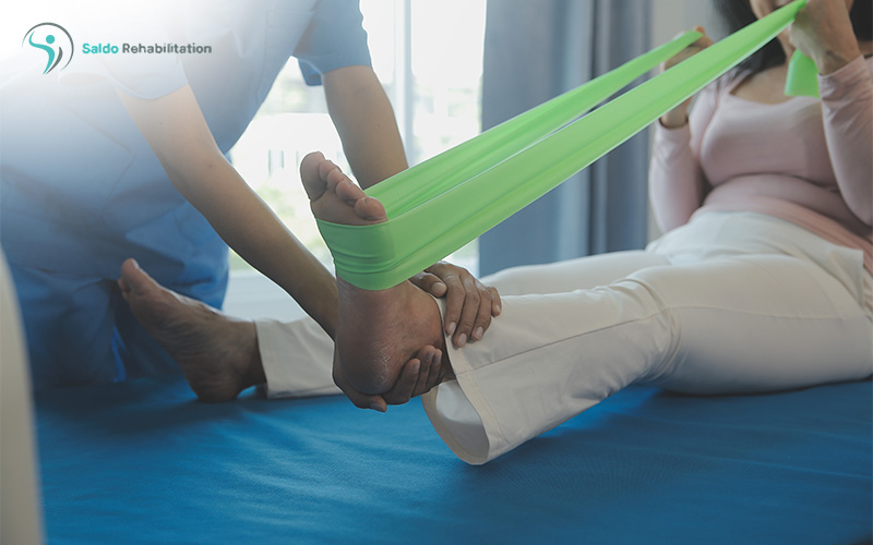 Physiotherapist helping a patient exercise her foot and knee